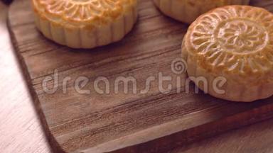 女人把一个漂亮的即食月饼放在木制托盘上，用于下午茶，中秋节的习俗观念，特写